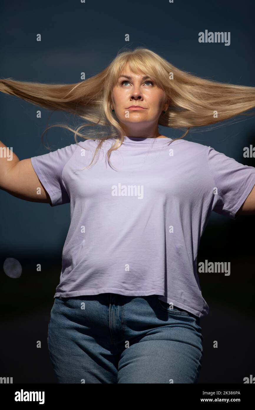 Pralle Frau mittleren Alters posiert in Jeans auf der Straße, übergewichtig xxl. Ein volles Mädchen genießt das Leben. Stockfoto