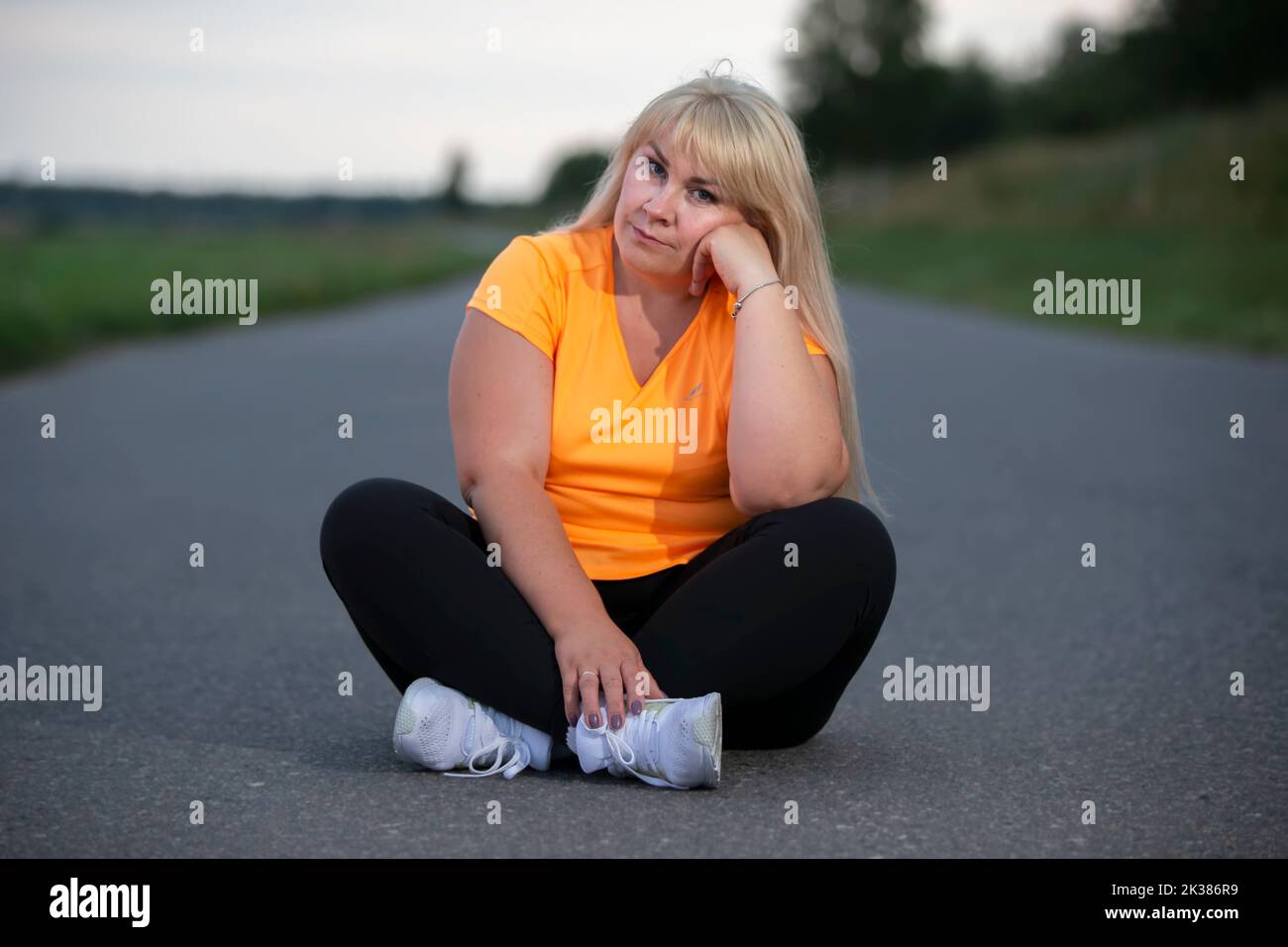 Porträt einer europäischen Frau mittleren Alters in einem Trainingsanzug, posiert für die Kamera, entspannend. Aufgeregt übergewichtige Frau im trendigen Trainingsanzug nach e ruhen Stockfoto