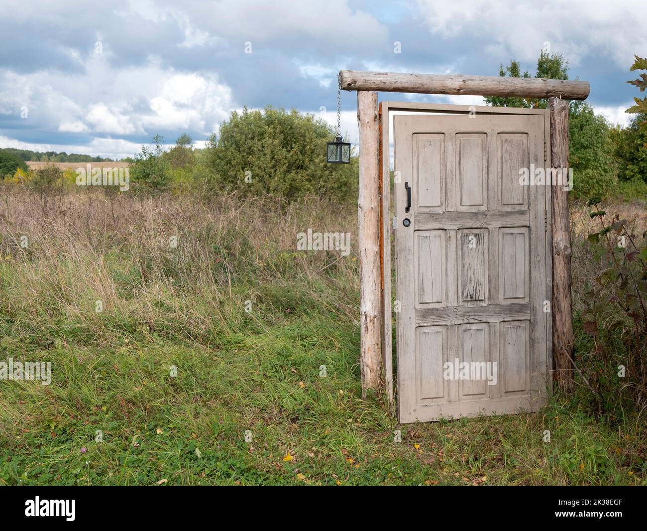 Entriegelte Tür, die ins nichts führt, Kopierraum. Altes Mystery-Portal im offenen Feld, selektiver Fokus Stockfoto