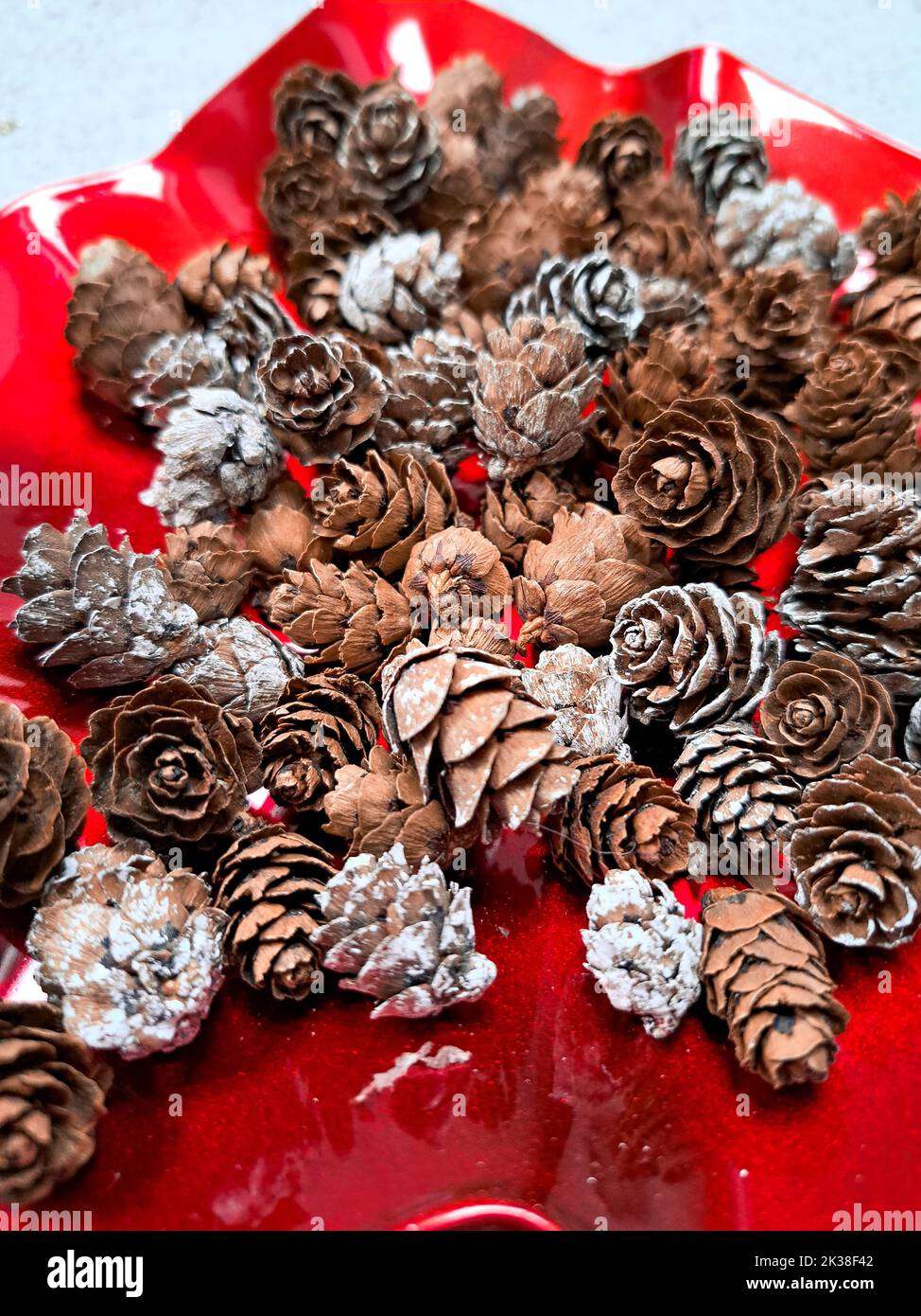 Nahaufnahme von kleinen Tannenzapfen auf rotem Teller weihnachtsdekor Hintergrund Stockfoto