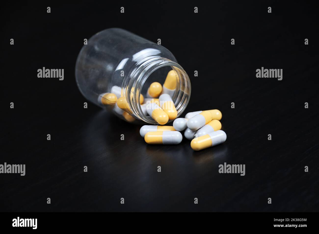 Pillen auf schwarzem Holztisch, Flasche mit verstreuten Kapseln. Antidepressiva, Vitamine für die Immunität in der Grippesaison Stockfoto