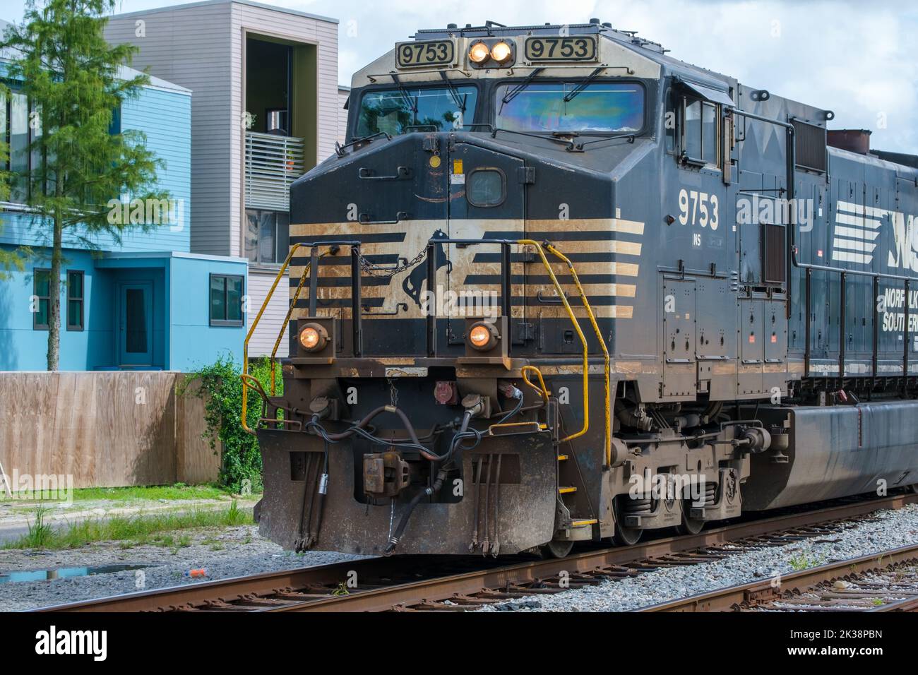 NEW ORLEANS, LA, USA - 12. AUGUST 2022: Norfolk Southern Lokomotive fährt nach Westen mit Wohngebäude im Hintergrund in Uptown New Orleans Stockfoto