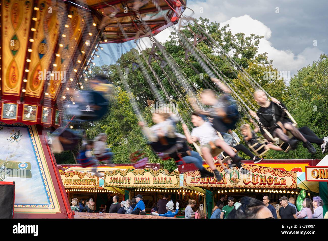 Auf der traditionellen Chair-O-Plane-Vergnügungsfahrt im Carters Vintage Steam Funfair, Basingstoke war Memorial Park, England, schweben Menschen herum Stockfoto