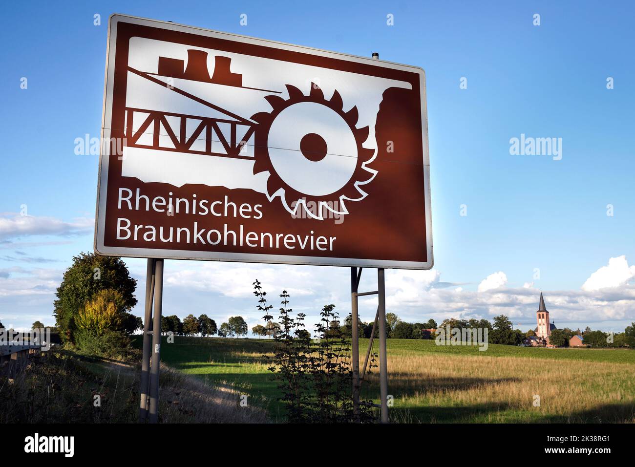 Schild mit symbolischem Schaufelradbagger an der Autobahn A44 bei Hasselweiler in Nordrhein-Westfalen. Die sogenannte "Tourist-Info-Tafel" verweist auf die industriekulturelle Attraktion des rheinischen Braunkohleglockenbergbaus, in dem Braunkohle in Tagebauen in riesigen Gruben abgebaut wird. Stockfoto