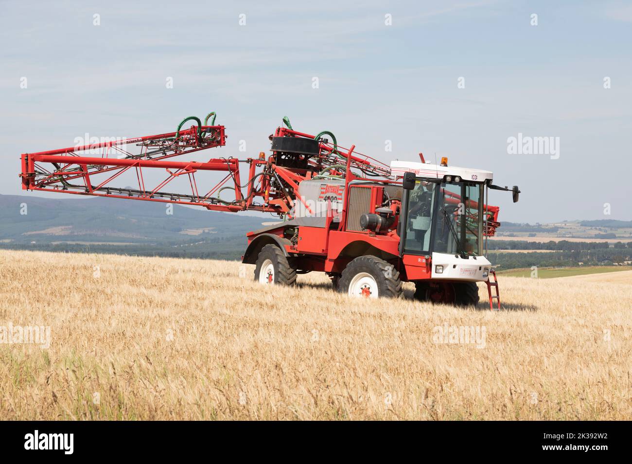 Ein Bateman Crop Sprayer faltet seinen Sprühboom in einem Gerstenfeld in der schottischen Landschaft Stockfoto