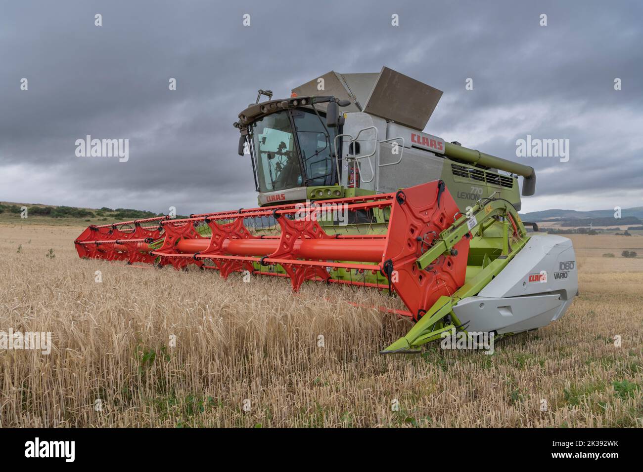 Ein Claas kombinieren Harvester Close Up, Ernte in einem Feld von Gerste an einem bewölkten Sommerabend Stockfoto