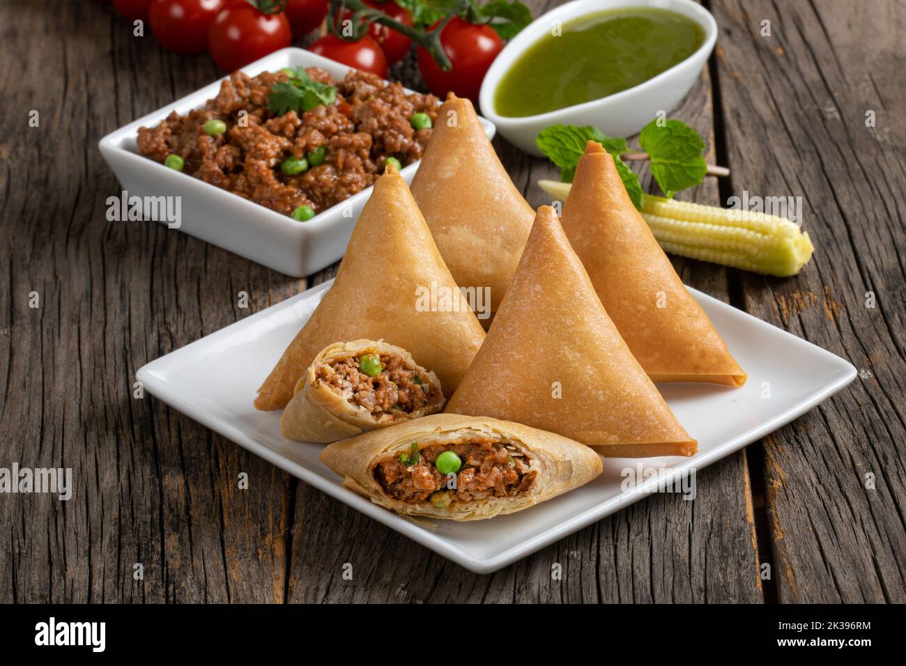 Süßes, leckeres, gebratenes indisches Gericht Samosha.Indisches köstliches tiefgebratenes Frühstück Samosa auch als Samoosa auf Holztextur Hintergrund isoliert bekannt Stockfoto