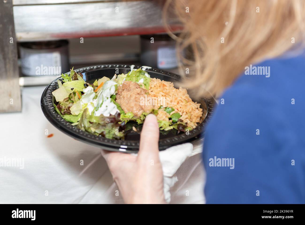 Partygast hat während des Mittagessens Teller voll mit Reis, Bohnen und Salat vom Buffet. Stockfoto