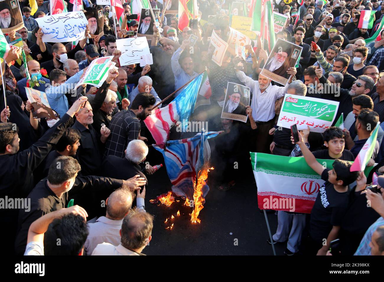 Teheran, Teheran, Iran. 25. September 2022. Regierungsnahe Demonstranten verbrennen während einer Kundgebung Darstellungen der britischen, israelischen und US-amerikanischen Flaggen, um die jüngsten regierungsfeindlichen Unruhen wegen des Todes einer jungen Frau in Polizeigewahrsam in Teheran, Iran, am 25. September 2022 zu verurteilen. Die Krise, die sich im Iran ausbreitet, begann als öffentliche Ausschüttung über den Tod von Mahsa Amini, einer jungen 22-jährigen Frau aus Saqqez, einer nordwestlichen kurdischen Stadt, die letzte Woche von der Moralpolizei des Landes in Teheran verhaftet wurde, weil sie angeblich gegen die strikt erzwungene Kleiderordnung verstoßen hatte. Kredit: ZUMA Press, Inc./Alamy Live Nachrichten Stockfoto