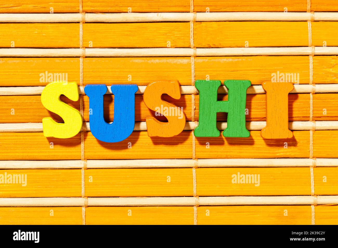 Sushi-Wort - Aufschrift mit bunten Buchstaben auf Bambusmatte Stockfoto
