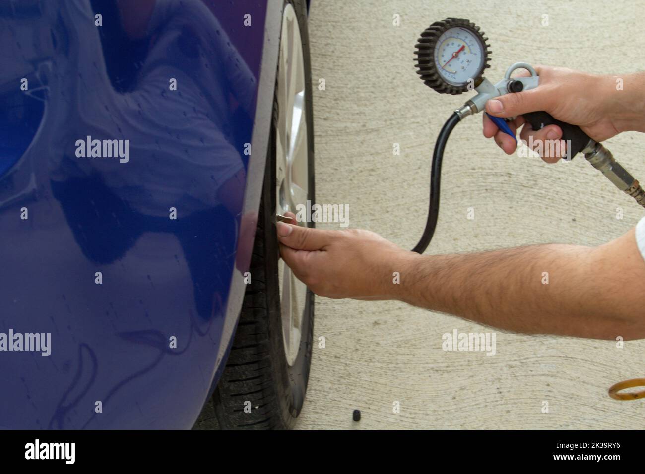 Bild von den Händen eines Mannes, der mit einer Pistole und einem Manometer die Reifen des Autos aufbläst. Fahrzeugpflege und richtiger Druck für den Kraftstoffverbrauch Stockfoto