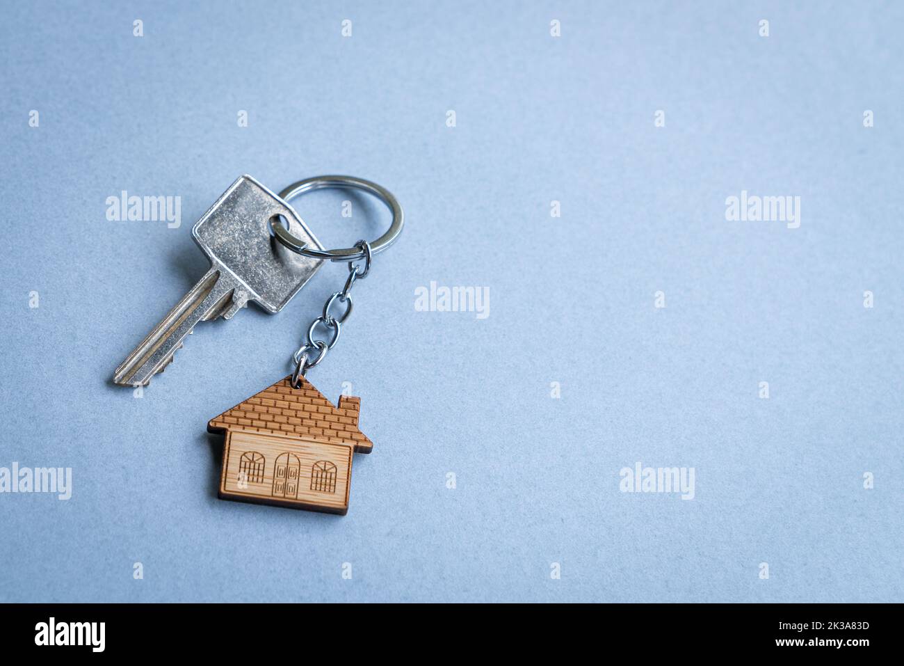 Schlüsselanhänger in Hausform auf blauem Hintergrund. Speicherplatz kopieren. Stockfoto