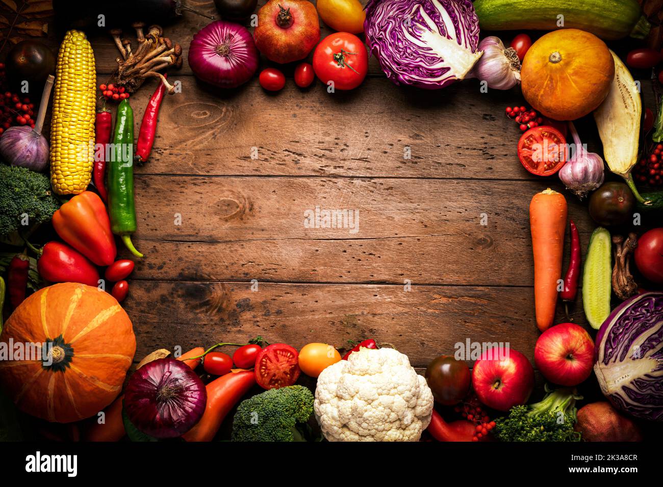Rahmen aus Gemüse und Obst auf einem hölzernen Hintergrund. Rustikaler Hintergrund über frische Ernte und gesunde Lebensmittel. Stockfoto
