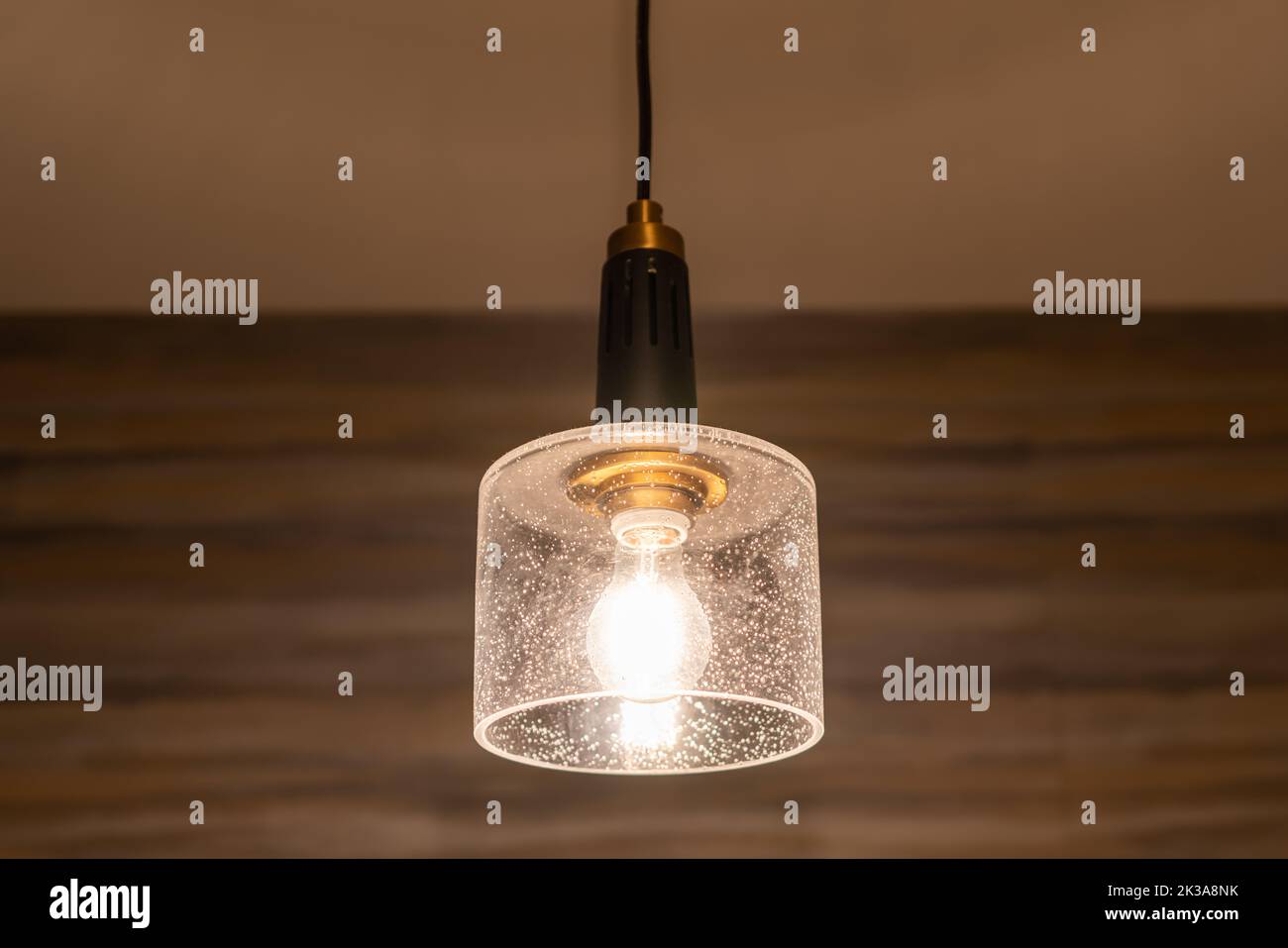 Hängende Glühbirne mit Wolfram-Filamenten mit einem Wandhintergrund. Stockfoto