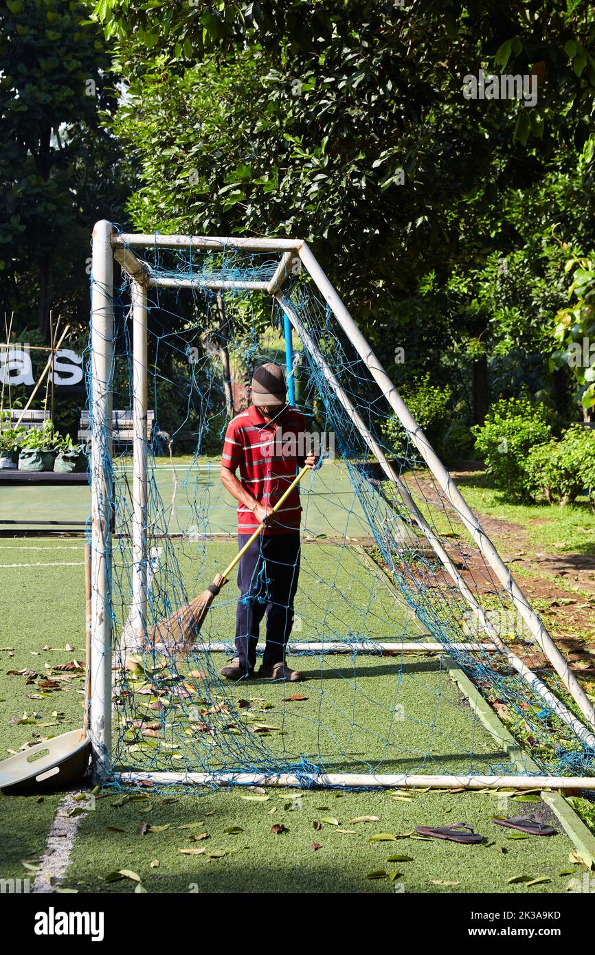 Ein Hausmeister reinigt das Fußballfeld, insbesondere das Tor, von trockenem Laub Stockfoto