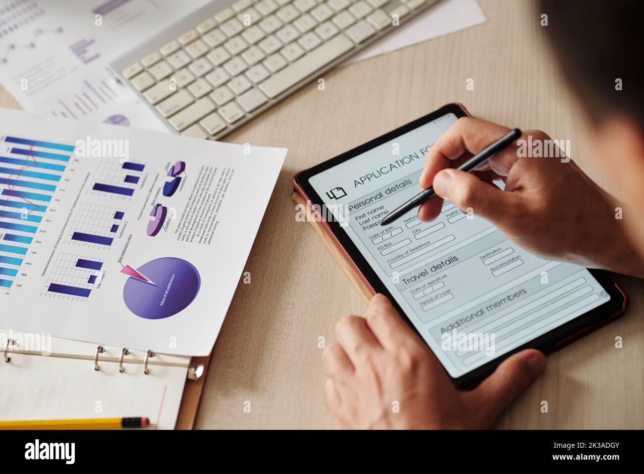 Nahaufnahme eines Geschäftsmannes, der persönliche Daten in einem Antragsformular auf einem digitalen Tablet schreibt Stockfoto