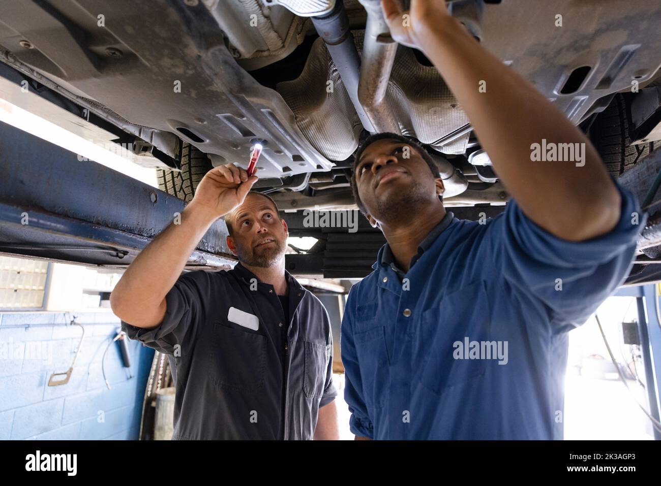 Mentor und Mechaniker, die sich in der Werkstatt mit dem Fahrgestell des Fahrzeugs befreunden Stockfoto