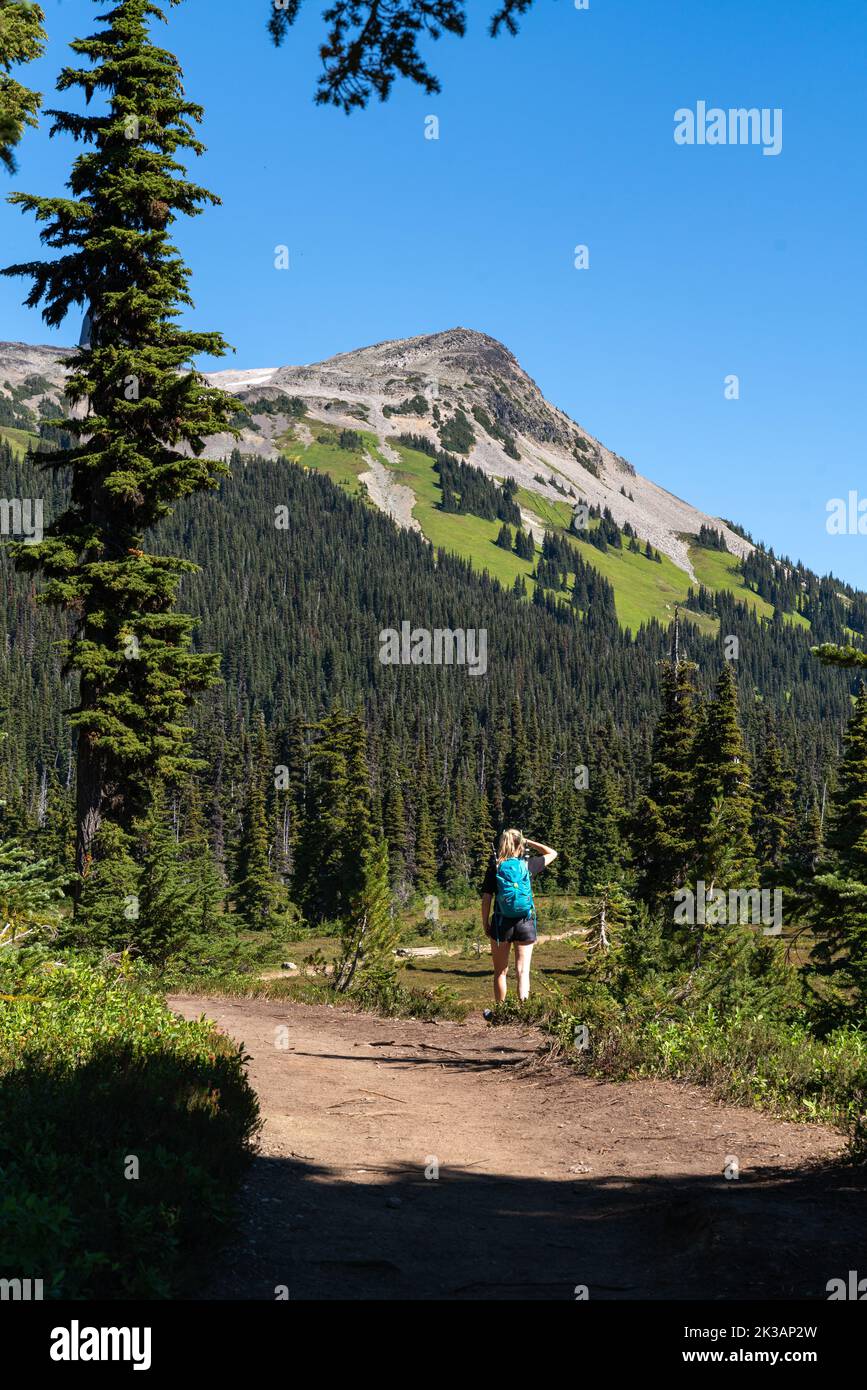 Eine Frau wandert an einem wunderschönen Sommertag auf einem Pfad im Garibaldi Provincial Park mit Black Tusk Mountain im Hintergrund. Stockfoto