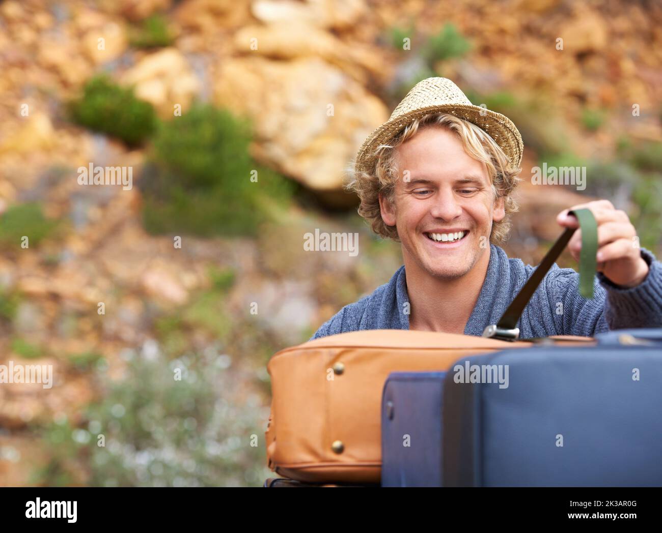 Sein Gepäck ausladen. Ein blonder Mann entlädt sein Gepäck auf einem Campingausflug. Stockfoto