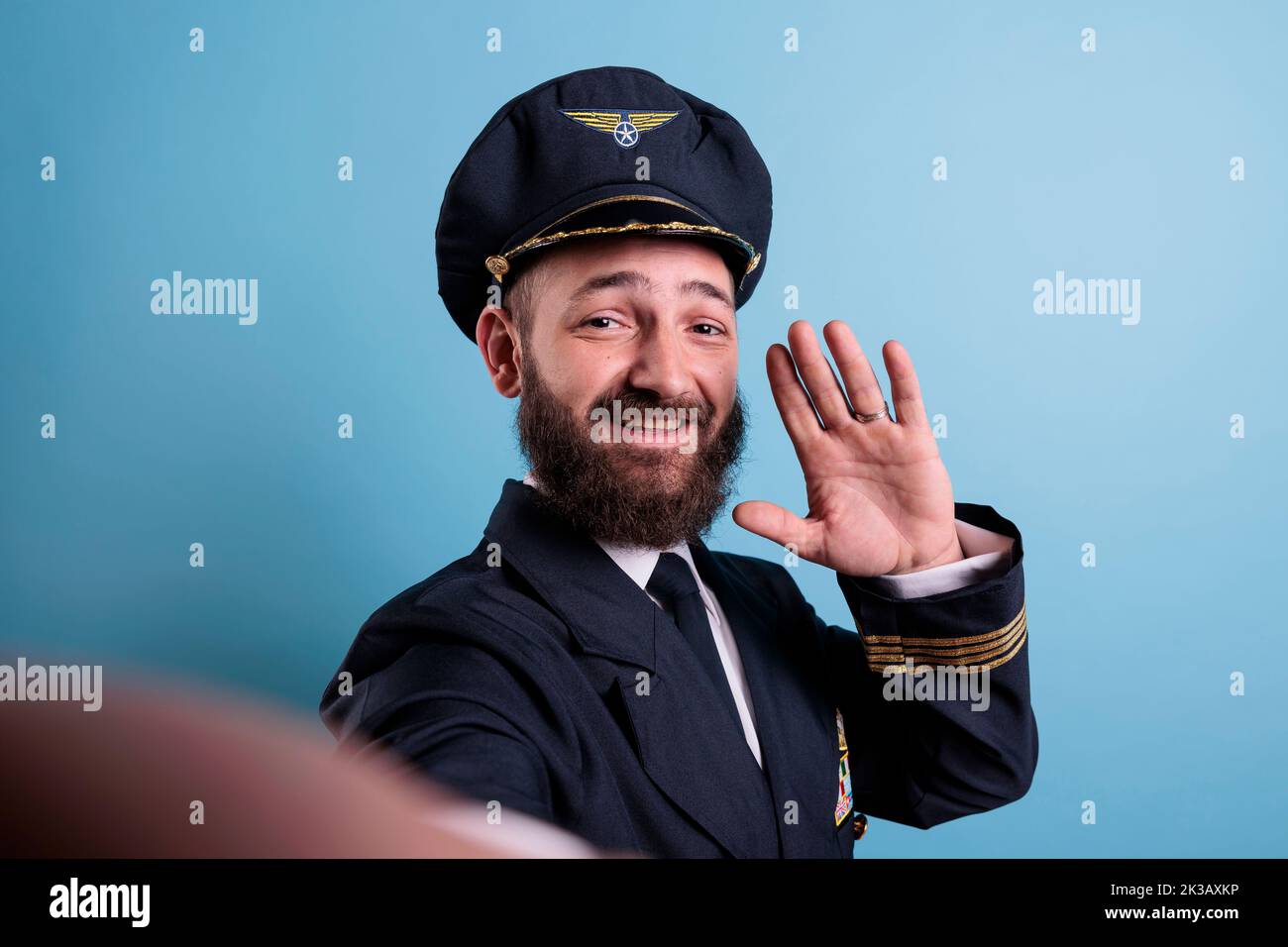 Pov lächelnder Flieger begrüßt die Kamera, macht Selfie auf der vorderen Smartphone-Kamera, fpv. Flugzeugpilot im mittleren Alter in Luftfahrtaubenuniform, Fotoaufnahme auf Mobiltelefon. Blick auf die erste Person Stockfoto