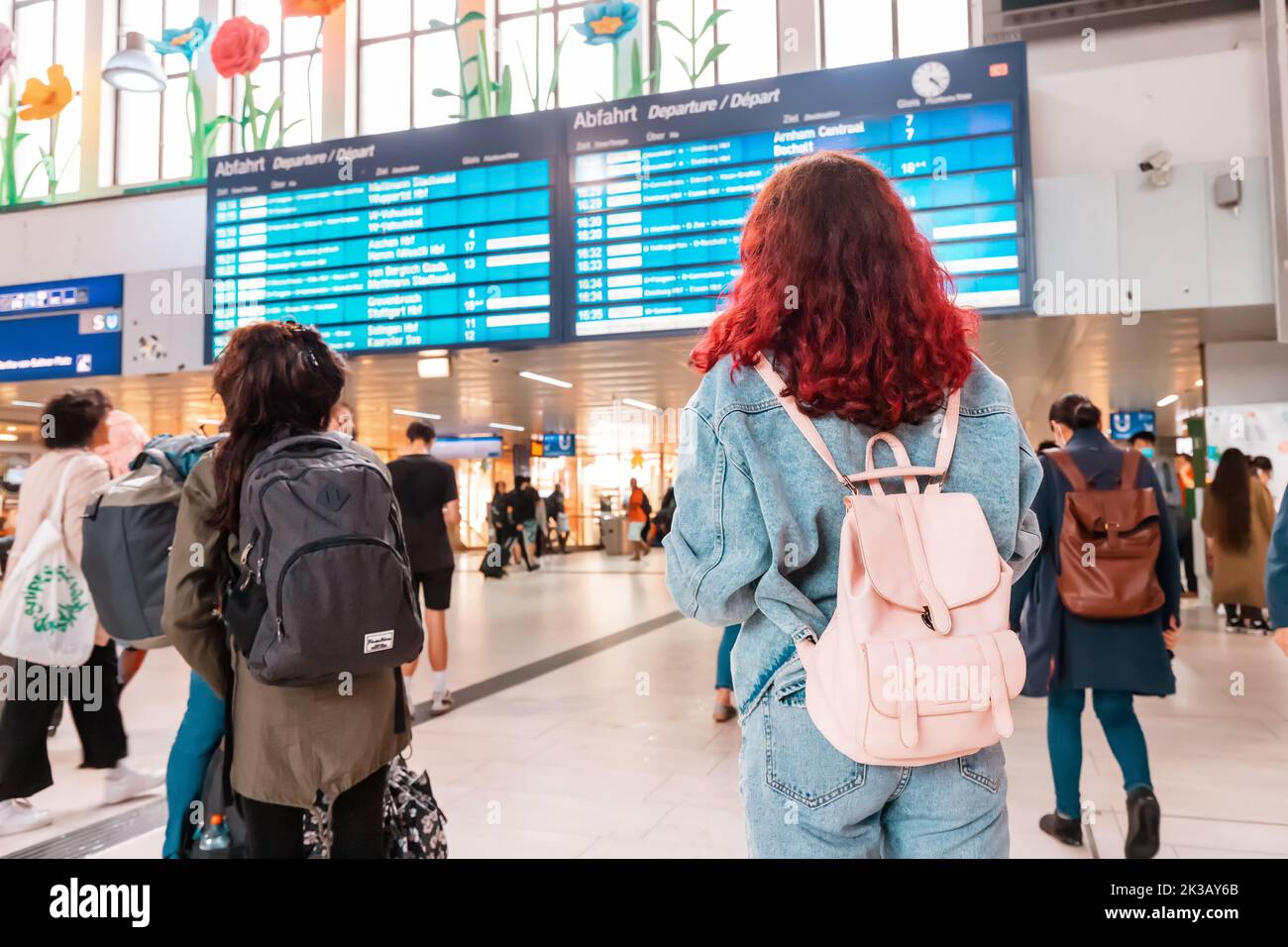 21. Juli 2022, Düsseldorf, Deutschland: Mädchen mit Rucksack beim Betrachen des Fahrplans und Warten auf verspäteten Zug am Bahnsteig Stockfoto