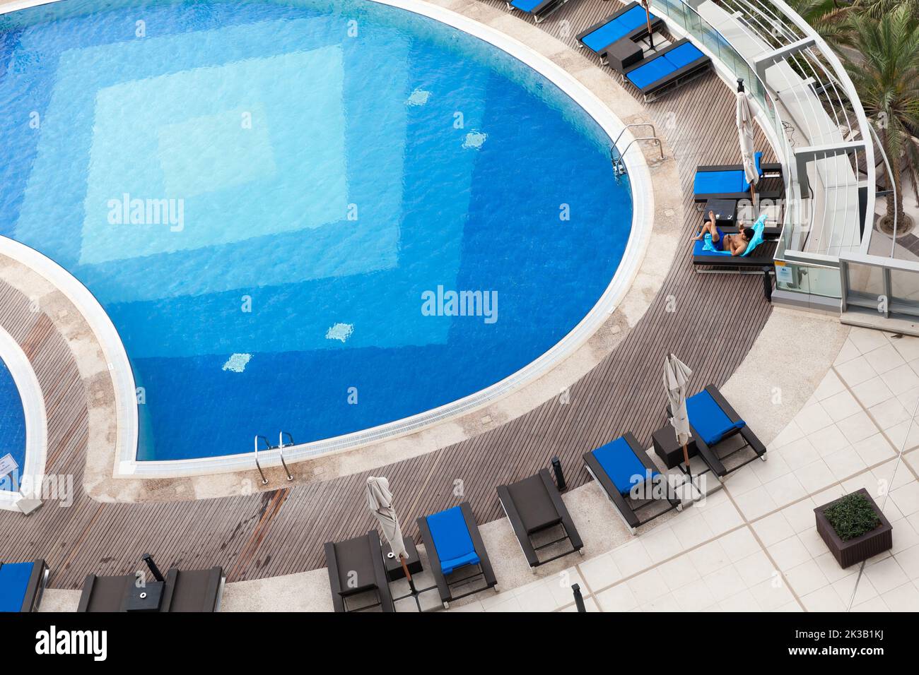 Abu Dhabi, Vereinigte Arabische Emirate - 8. April 2019: Blauer Pool aus der Luft, ein Mann entspannt sich in einer Liege Stockfoto