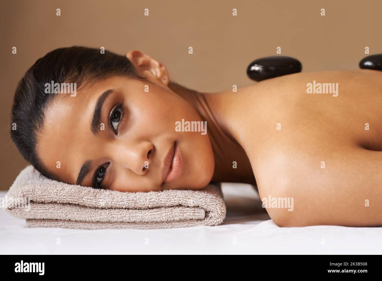 Hot Stone Entspannung. Eine junge ethnische Frau, die in einem Spa eine Behandlung mit heißen Steinen erhält. Stockfoto