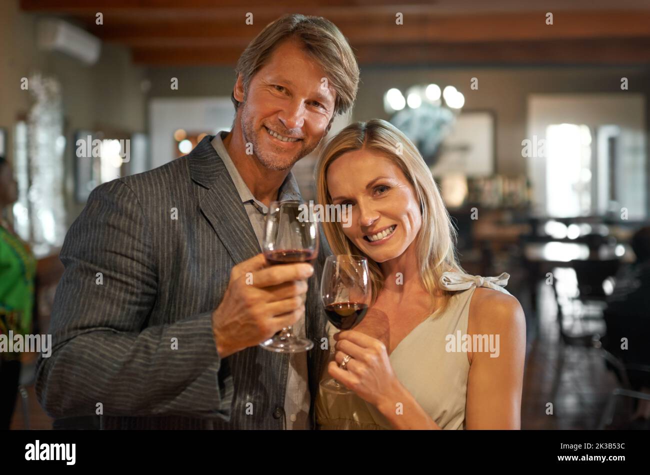 heres zu weiteren zehn Jahren zusammen. Ein glückliches Paar, das mit Gläsern Wein toaste. Stockfoto