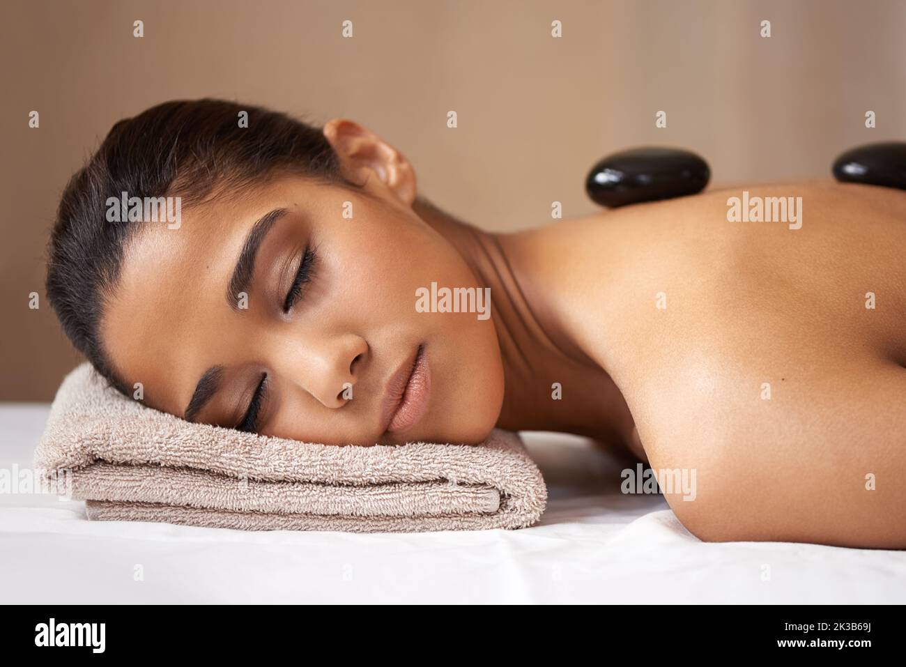 Entspannung der tiefen Muskeln. Eine junge Frau, die eine Behandlung mit heißen Steinen in einem Spa erhält. Stockfoto
