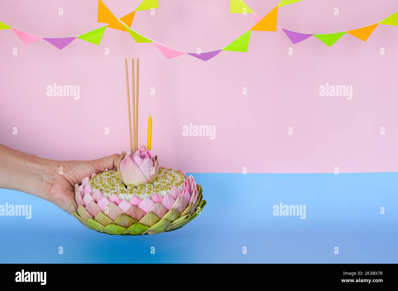 Das rosa Lotusblütenblatt krathong mit 3 Räucherstäbchen und Kerze ziert mit Lotus und Kronenblume, die von Hand für das Thailand Loy Krathong Festfest gehalten werden Stockfoto