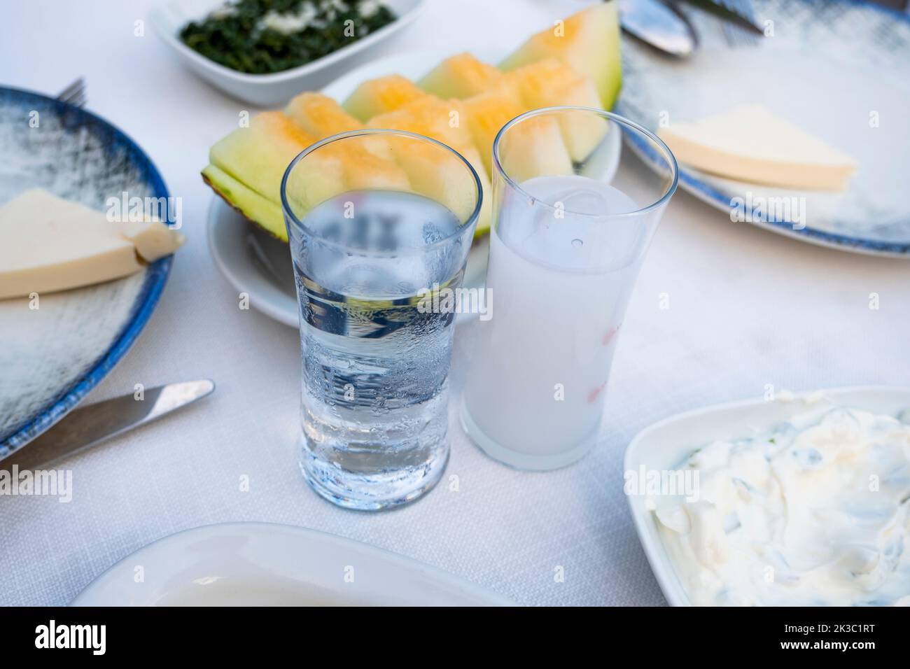 Türkisches Raki mit Wasser auf dem Tisch mit Melonenscheiben und Vorspeise, traditioneller türkischer Alkohol, bekannt als Rakı, chillen Sie mit Freunden im Restaurant Stockfoto