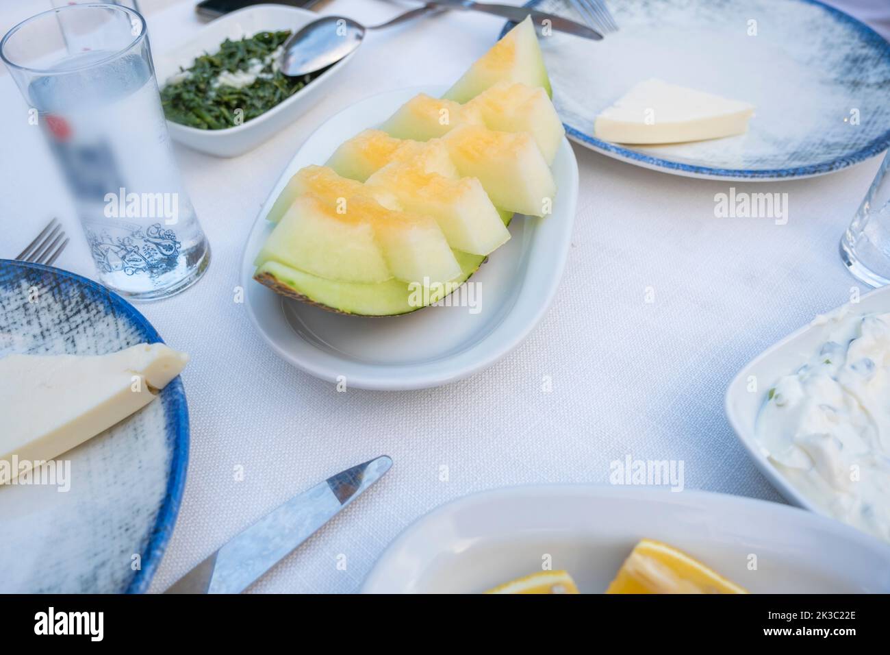 Melone auf einem Tisch mit Raki und Vorspeise, Abendessen und Mahlzeit Idee, traditionelle türkische Alkohol als Rakı bekannt, Lebensmittel auf einem Teller mit Messer Stockfoto