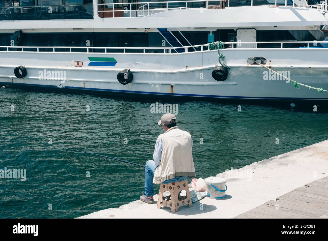 Zurück gedreht alten Mann Angeln, Angelkonzept, Eminonu Karkoy seasıde, ältere Mann Hobbys Idee, ruhig und entspannt, Fähre im Hintergrund Stockfoto