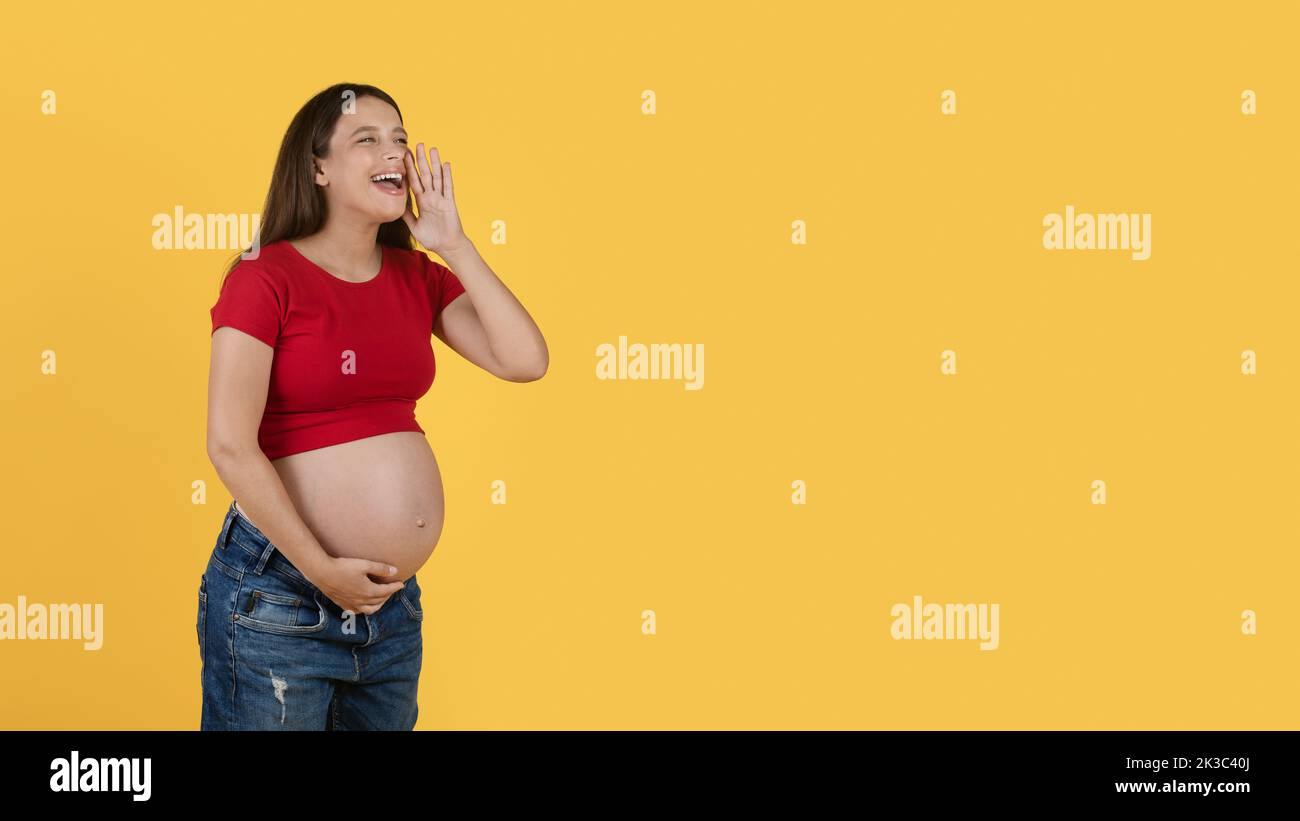 Glückliche Junge Schwangere, Die Ankündigung Macht Und Über Gelben Hintergrund Schreit Stockfoto