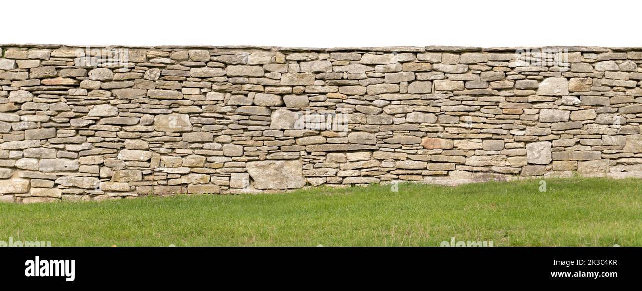 Hellbraune gelbe Trockensteinwand, schräg anfallender Boden mit Gras am Boden, weißer Himmel, Sandstein-Gartenwand Hintergrund Stockfoto