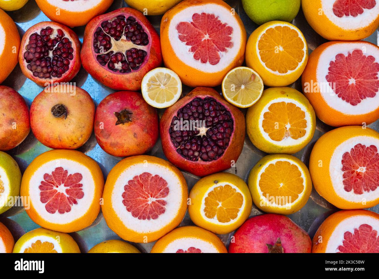 Bunt geschnittene Früchte, Hintergrund mit frischen Bio-Zitrusfrüchten, gesundes Leben und vegetarische Idee, farbige saftige Früchte, geschnittene Granatapfel-Orange Grapefruit Stockfoto