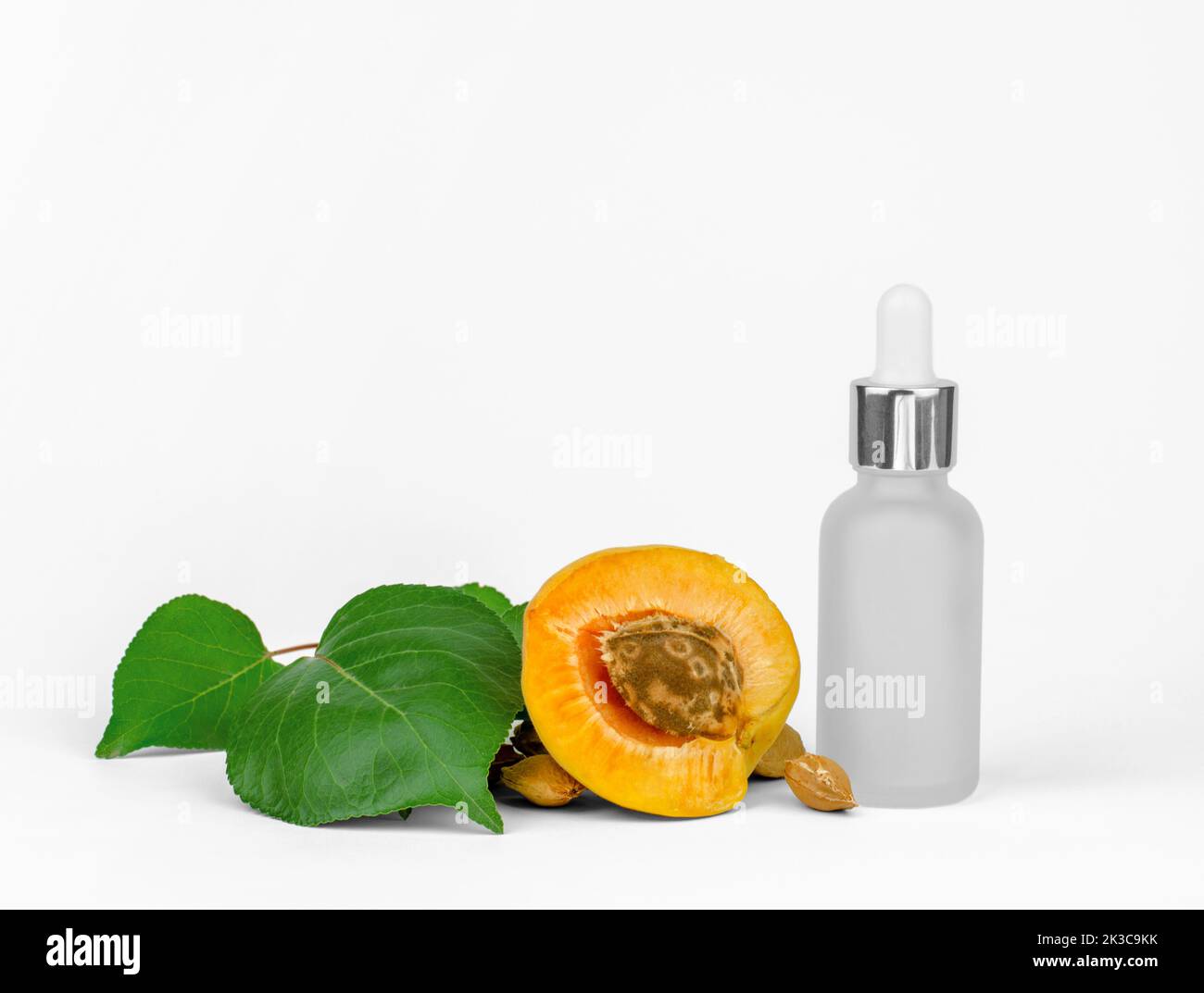 Kosmetikflasche mit Gesichtsserum und frischen Aprikosen. Haut- und Haarpflege, ätherisches Aprikosenöl Stockfoto