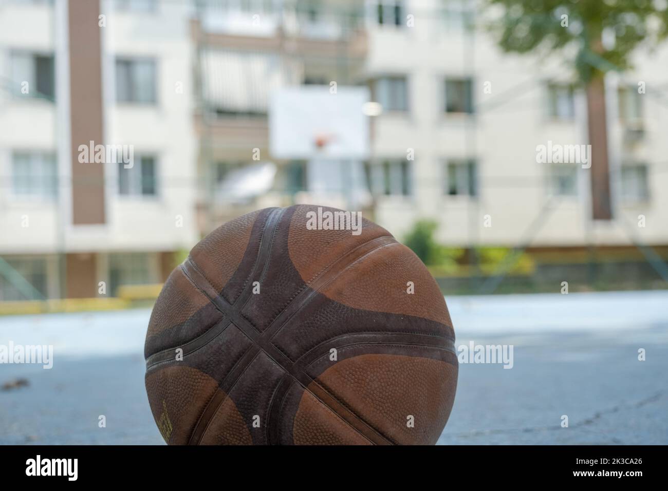 Selektiver Fokus-Basketballball mit Basketballkorb und Gebäuden, Street-Basketball-Konzept, No People-Basketballplatz, Vorort- und Outdoor-Sport Stockfoto