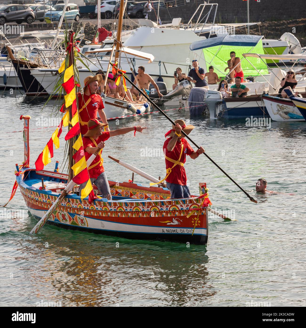 Das jährliche Fest der 'U Pisci a Mari' im sizilianischen Dorf Aci Trezza, in der Nähe von Catania. Dies findet um das Fest der Geburt des hl. Johannes des Täufers Ende Juni statt. Es handelt sich um eine traditionelle Fischereiexpedition für Schwertfisch, die früher in der Straße von Messina stattgefunden hat. Die Rolle des Schwertfisches wird von einem Schwimmer gespielt, der wiederholt von den Fischern gefangen wird, blutig aufgeschnitten wird, dann aber irgendwie entkommen kann. Schließlich schafft es der „Schwertfisch“, das Boot umzustürzen. (Den „Schwertfisch“ ausspeien) Stockfoto