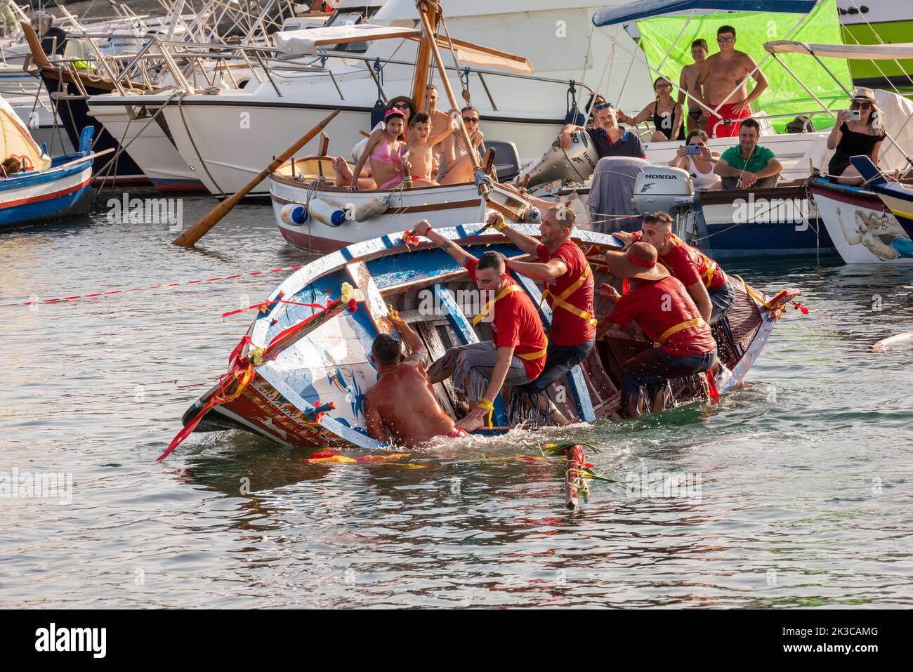 Das jährliche Fest der 'U Pisci a Mari' im sizilianischen Dorf Aci Trezza, in der Nähe von Catania. Dies findet um das Fest der Geburt des hl. Johannes des Täufers Ende Juni statt. Es handelt sich um eine traditionelle Fischereiexpedition für Schwertfisch, die früher in der Straße von Messina stattgefunden hat. Die Rolle des Schwertfisches wird von einem Schwimmer gespielt, der wiederholt von den Fischern gefangen wird, blutig aufgeschnitten wird, dann aber irgendwie entkommen kann. Schließlich schafft es der „Schwertfisch“, das Boot umzustürzen. Stockfoto