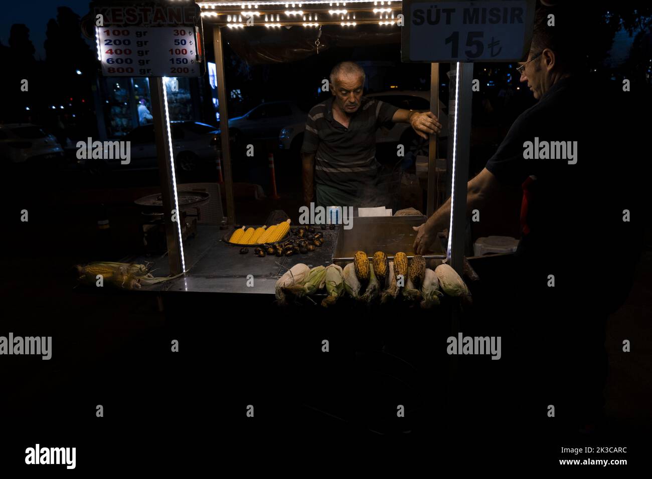 Maishändler mit einem Kunden, Nachtaufnahmen in Istanbul, Maisverkäufer mit Licht, Erkundung von Istanbul, Nachtleben-Idee Stockfoto