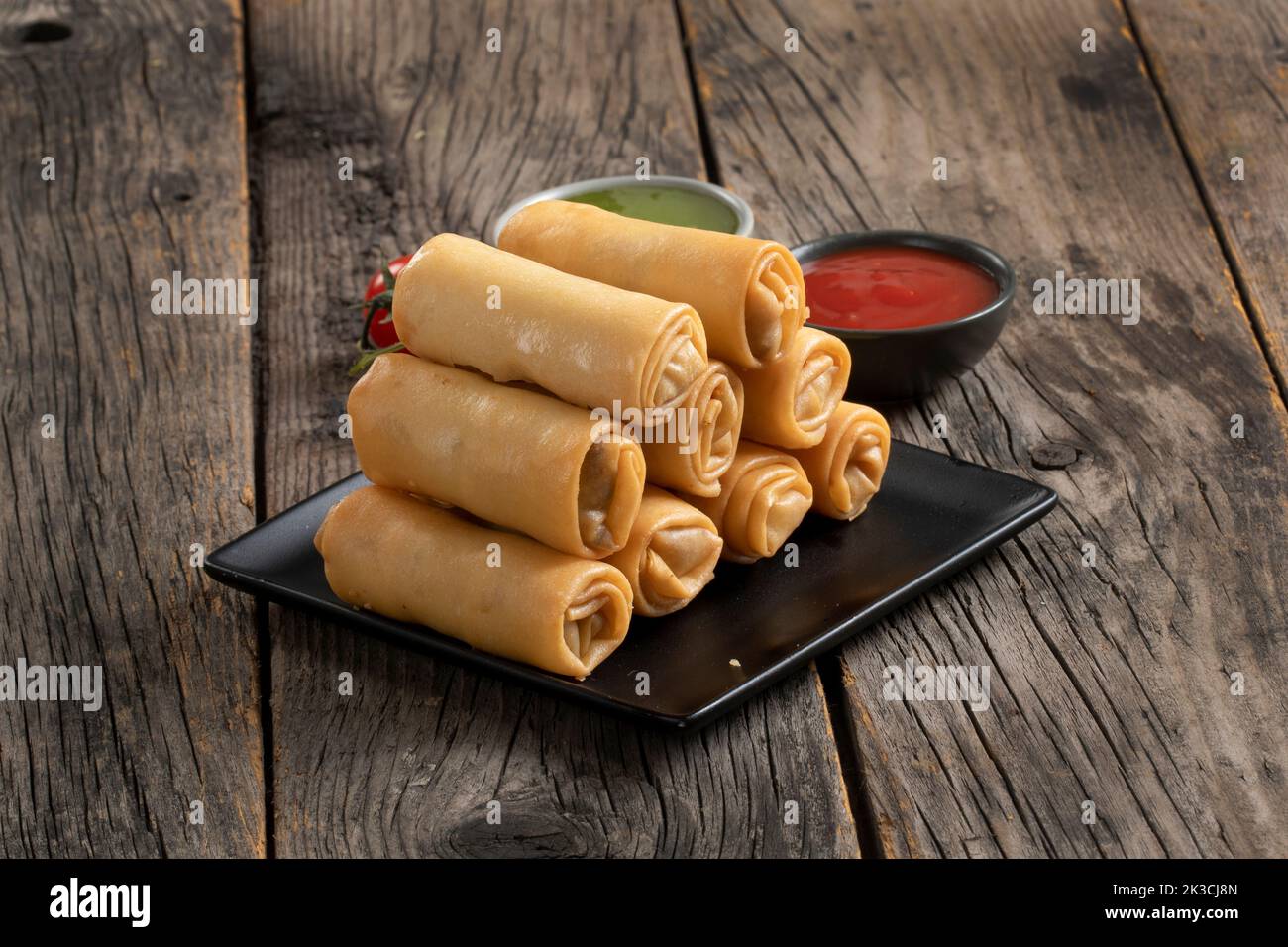 Gebratene Frühlingsrollen mit süßer Chilisauce und Limette auf dem Teller Stockfoto