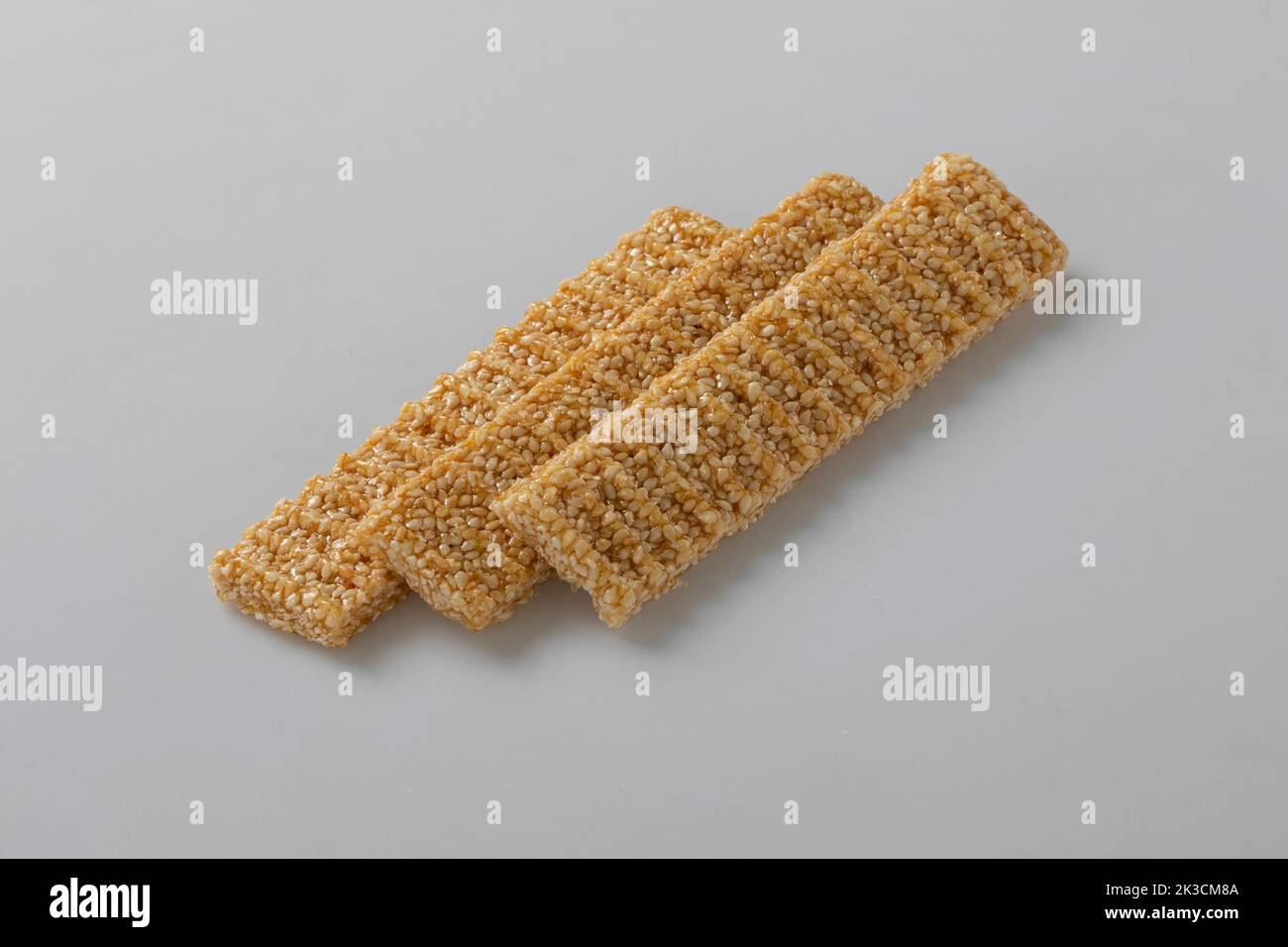 Sesamsamen-Bonbons, in einer Holzschale. Sesam spröde oder Crunch, eine Konfektion aus Sesamsamen und Honig, der in flache Riegel gepresst wird, ein beliebter Snack Stockfoto