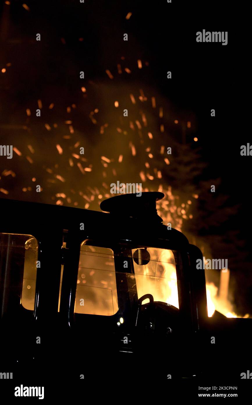 Die Kappe eines Militärs wurde auf das Dach eines 1934 Standard Ten gelegt, inmitten der flammenden Nachwirkungen des Brandbombenangriffs im Zweiten Weltkrieg. Stockfoto