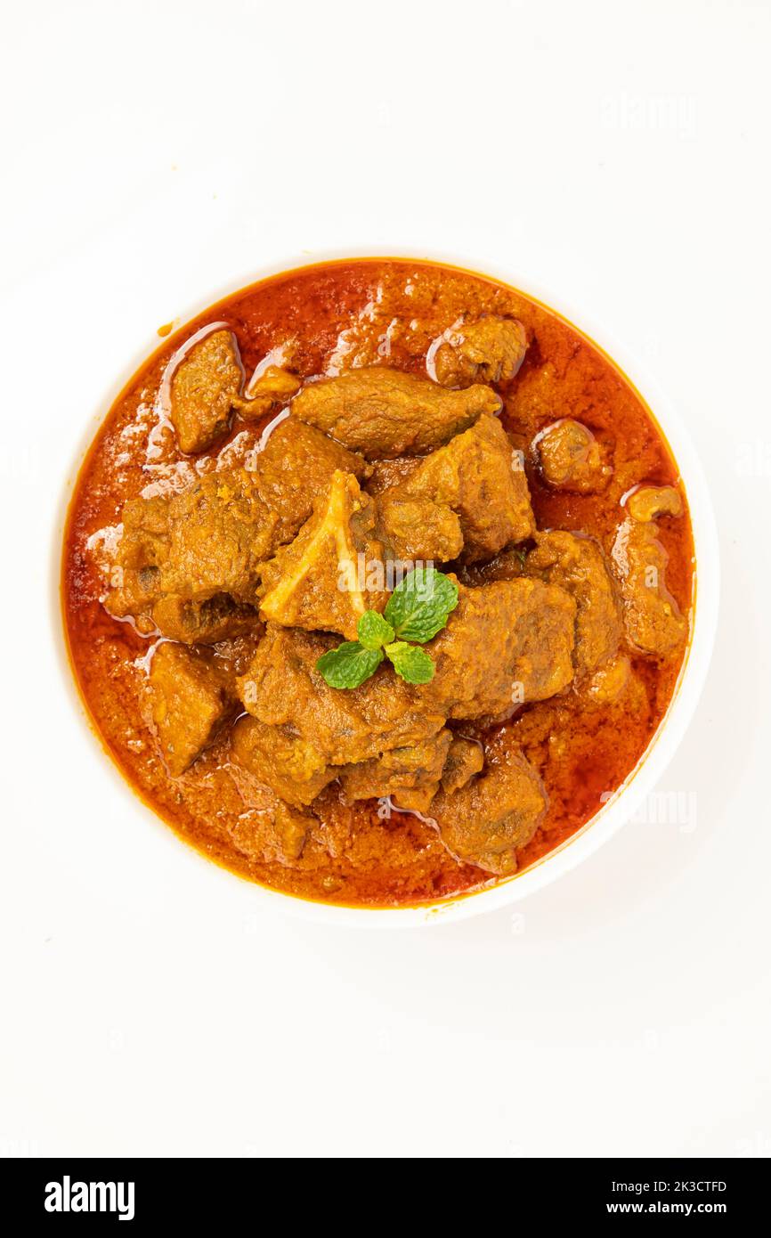 Rind-Masala oder Braten, kerala Stil hausgemachtes Rezept garniert mit Kokosnussstücken und Kerrgeblättern, die in einer weißen Schüssel mit weißem Hintergrund angeordnet ist Stockfoto