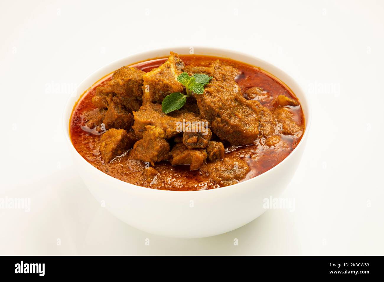 Rind-Masala oder Braten, kerala Stil hausgemachtes Rezept garniert mit Kokosnussstücken und Kerrgeblättern, die in einer weißen Schüssel mit weißem Hintergrund angeordnet ist Stockfoto