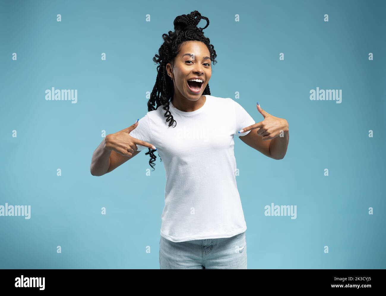 Lächelnde afroamerikanische Frau in einem weißen T-Shirt, die mit dem Finger auf ihr T-Shirt zeigt, zufriedene junge Kundin, die tolle Einkäufe macht Stockfoto