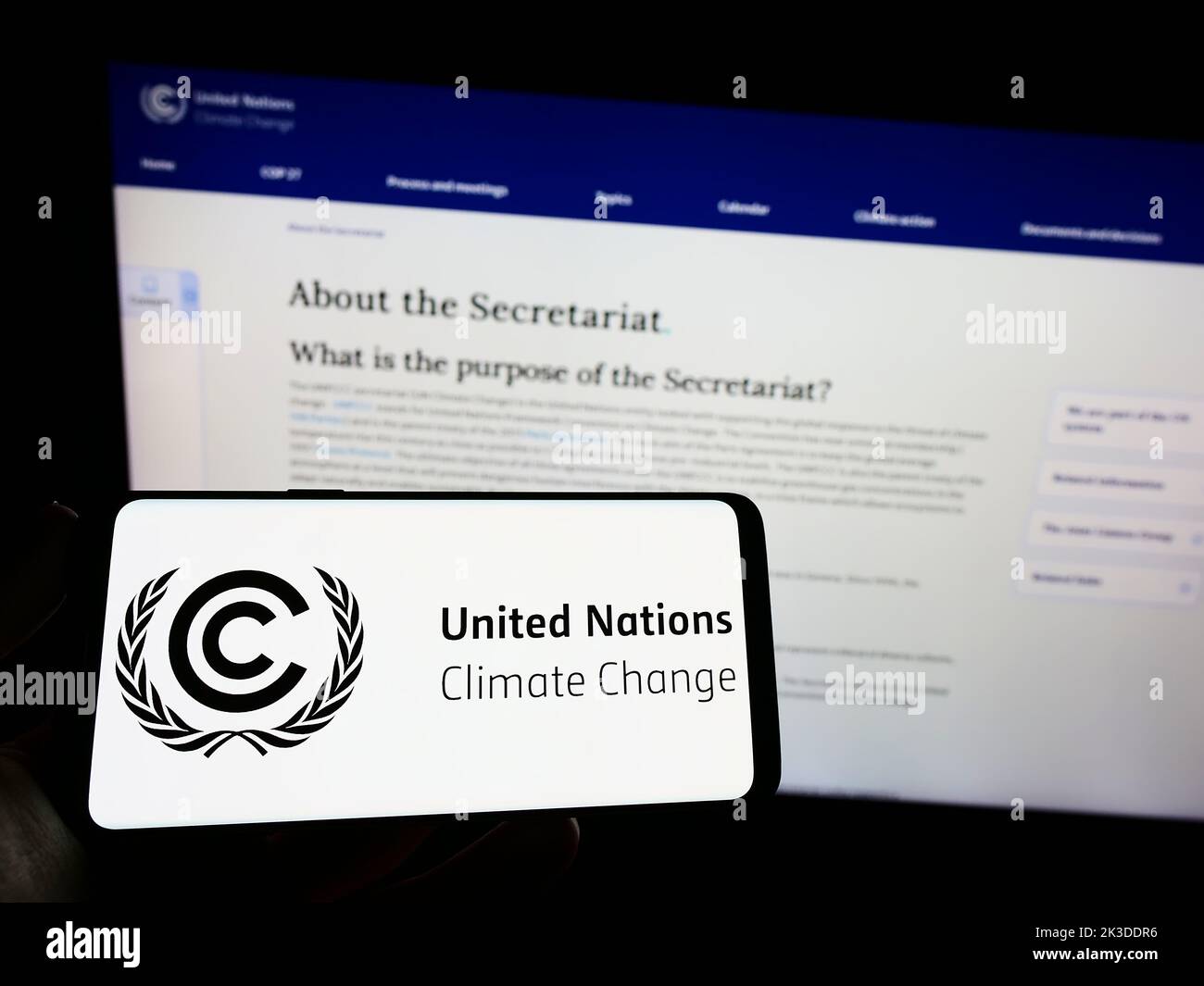 Person, die das Smartphone mit dem Logo des UN-Umweltabkommens UNFCCC auf dem Bildschirm vor der Website hält. Konzentrieren Sie sich auf die Telefonanzeige. Stockfoto
