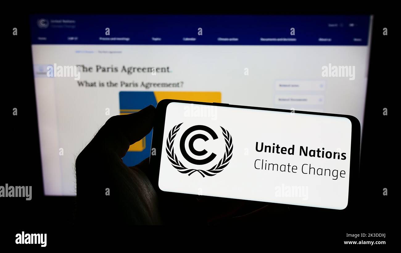 Person, die Mobiltelefon mit dem Logo des UN-Umweltabkommens UNFCCC auf dem Bildschirm vor der Webseite hält. Konzentrieren Sie sich auf die Telefonanzeige. Stockfoto