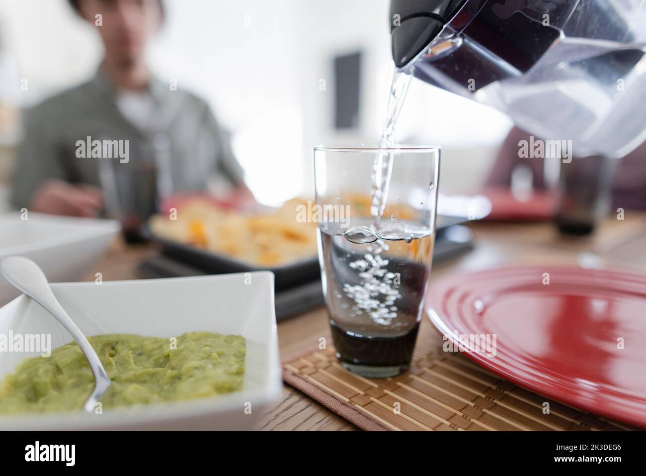 Nahaufnahme Krug Gießen gefiltertes Wasser in Glas am Tisch Stockfoto